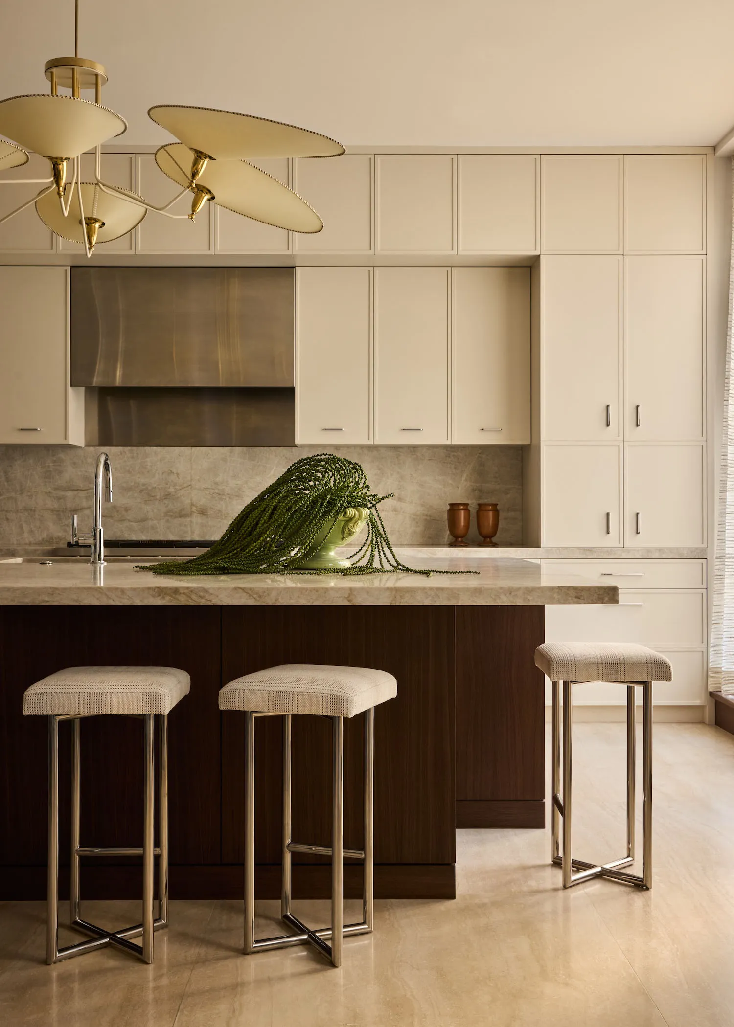 Modern kitchen with a marble countertop, stools, and a large window allowing natural light to enter the space