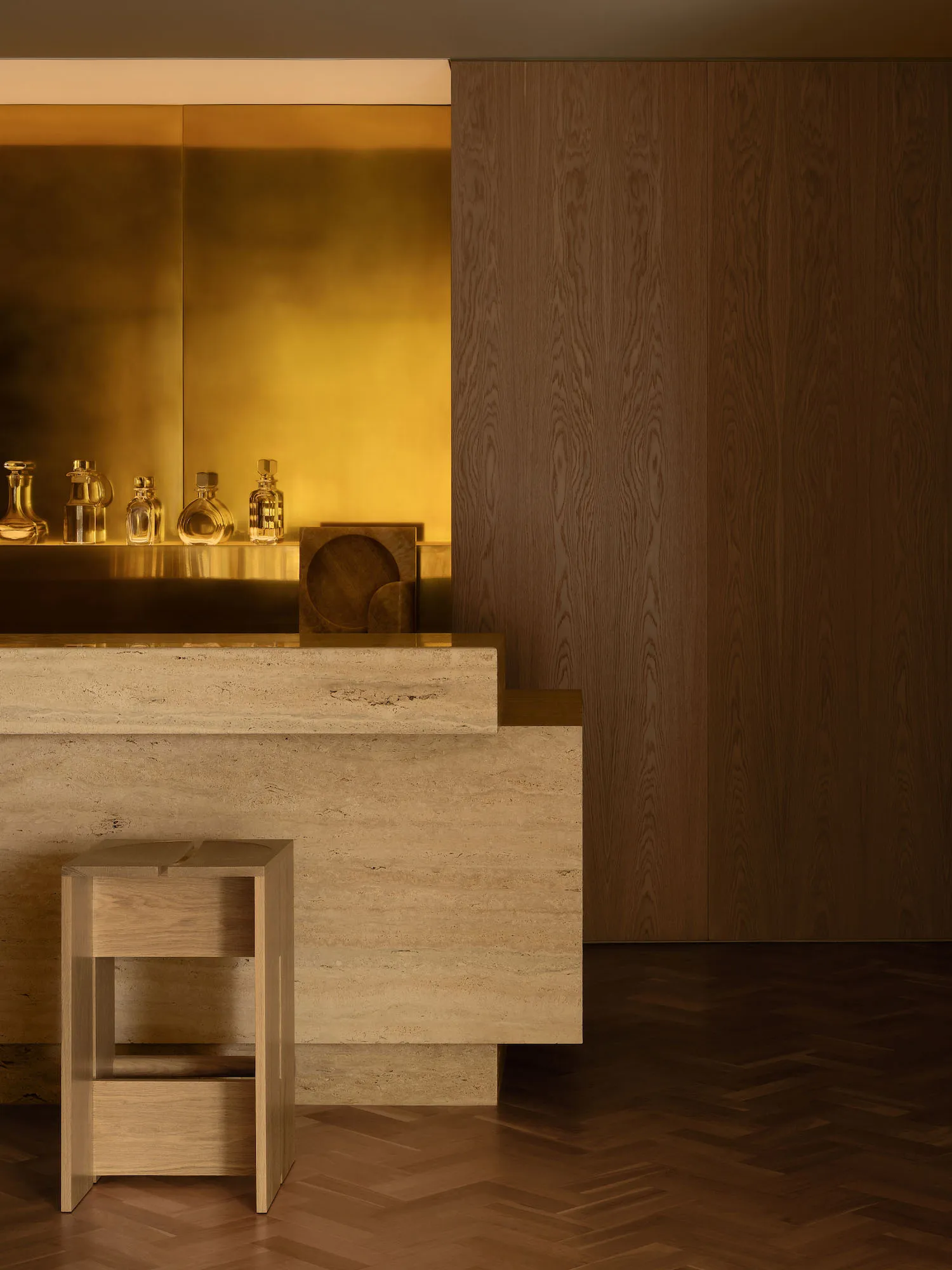 A dimly lit bar area with a wooden counter, bottles, and a stool, set against a wooden wall