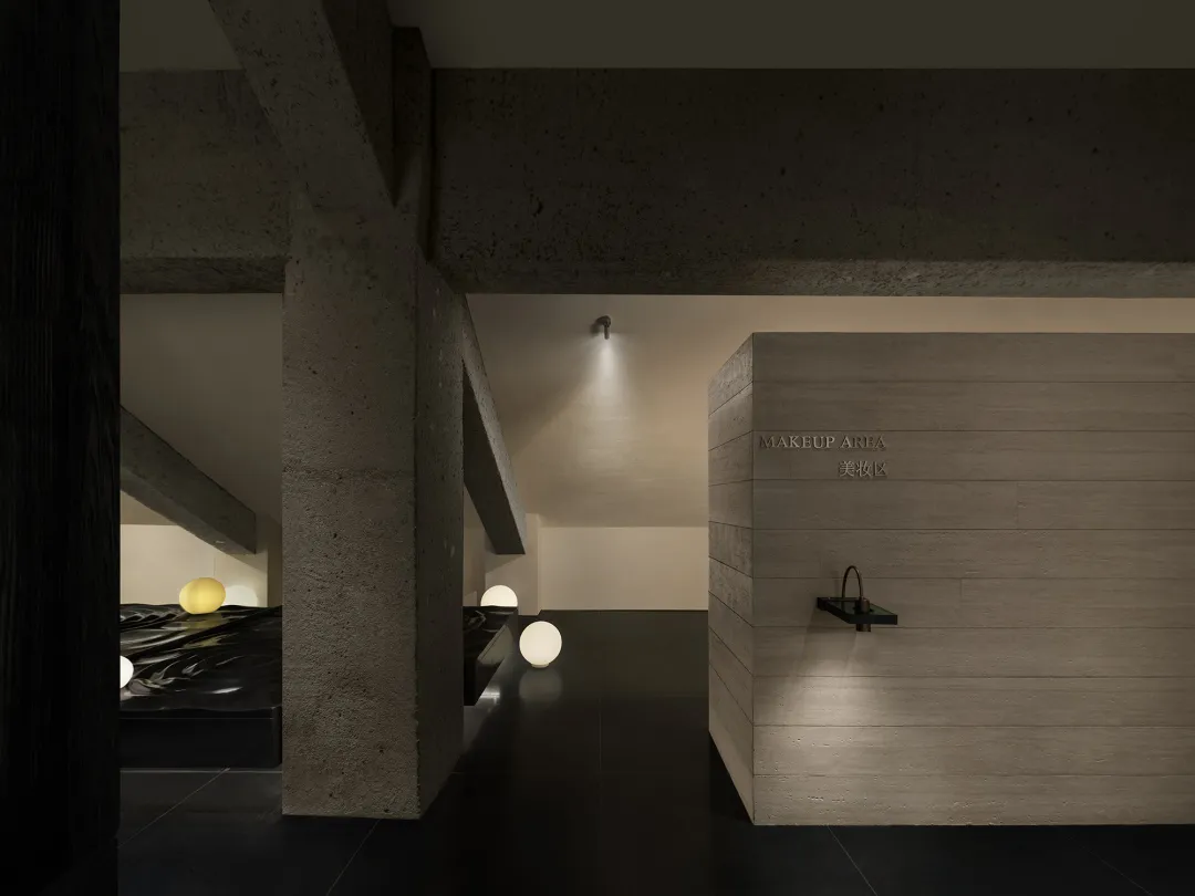 Dimly lit minimalist bathroom with a concrete wall, wooden door, and scattered small balls