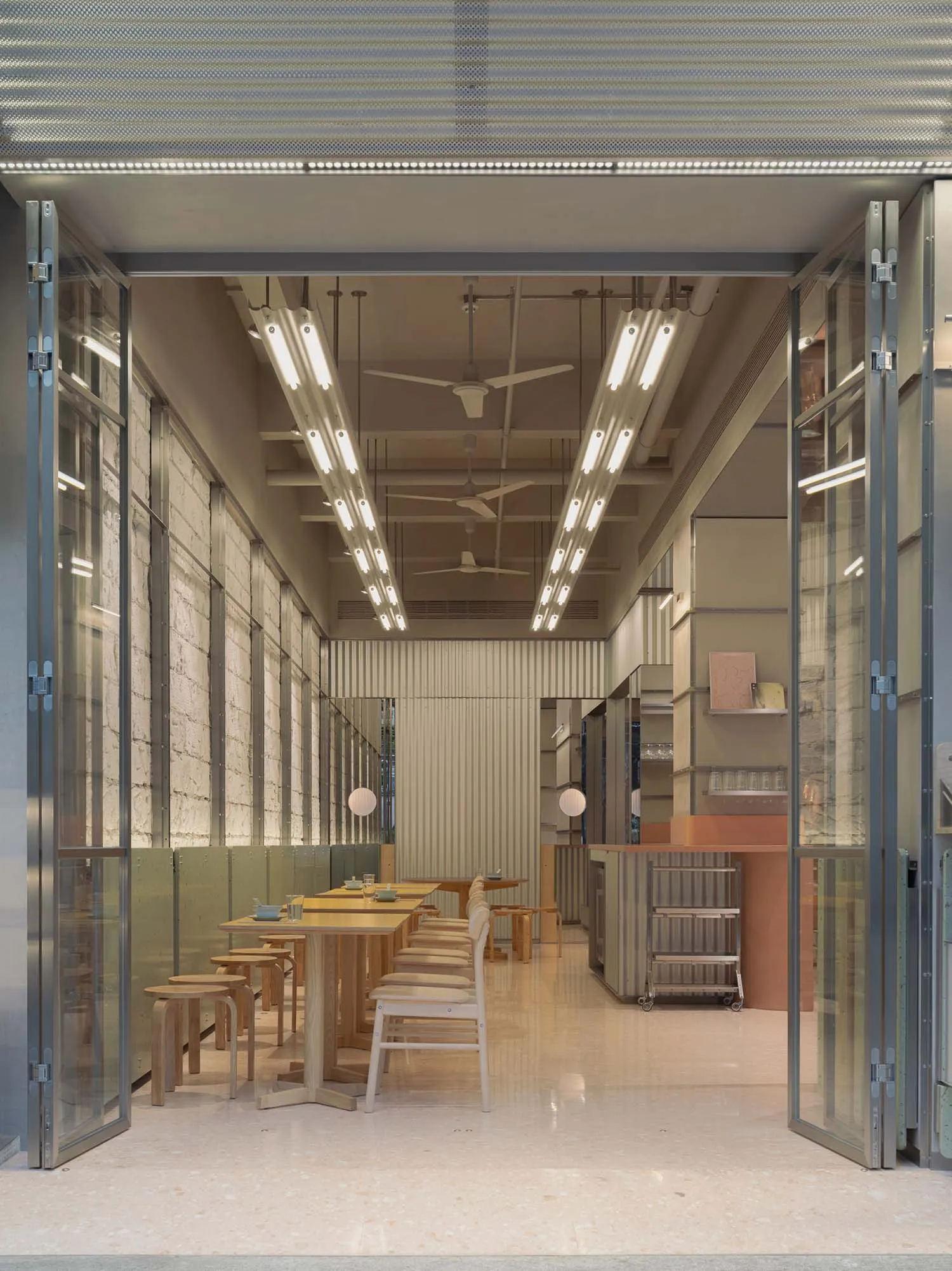 A modern dining space with multiple wooden tables and chairs, well-lit by natural light from windows, creating a bright and welcoming atmosphere
