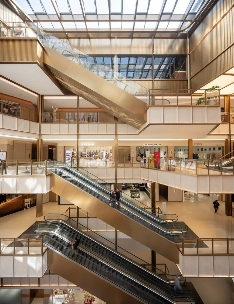 A large commercial building with a modern design, featuring a central metal spiral staircase, large glass windows, and bright lighting