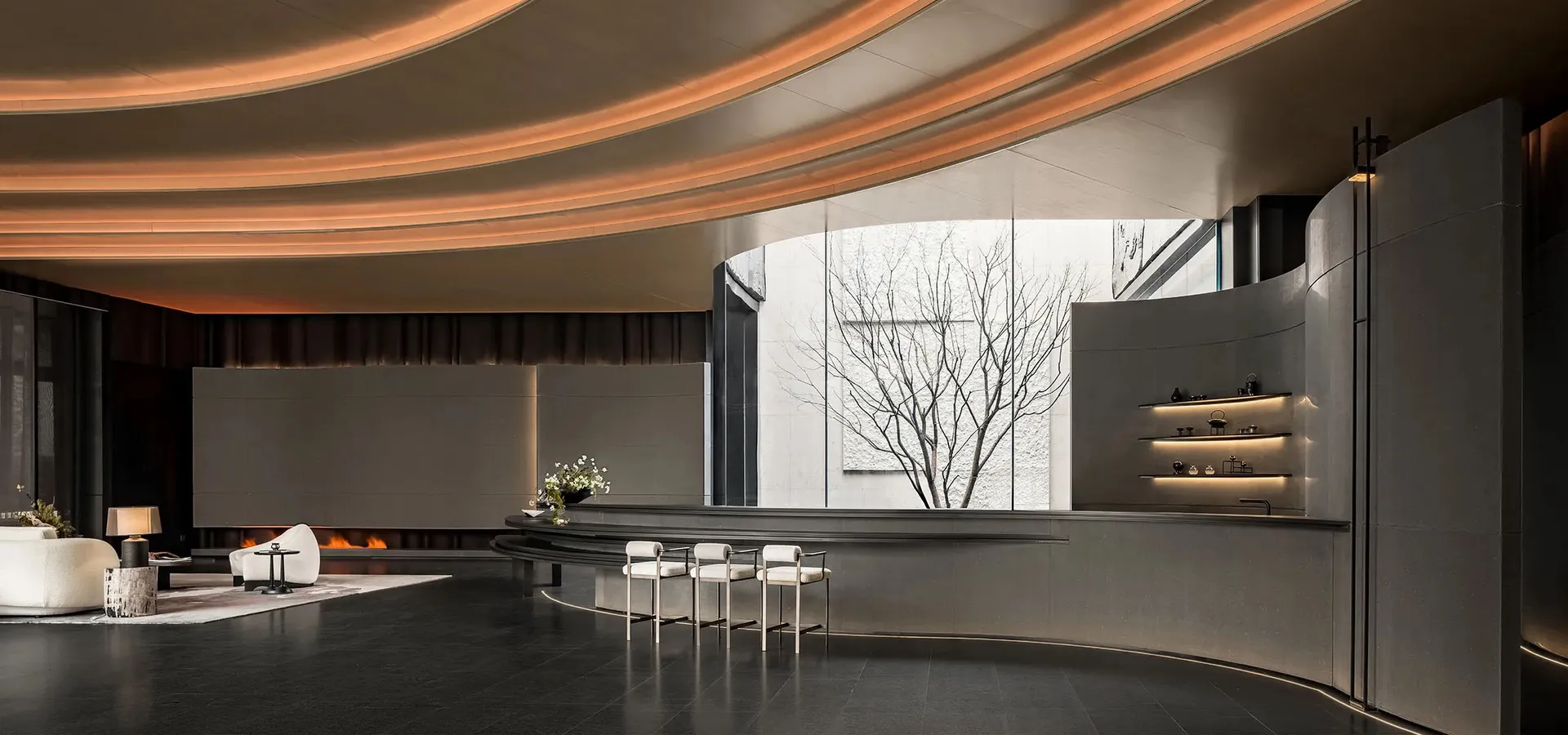 Modern lobby with a marble counter, white chairs, and natural light from a large window
