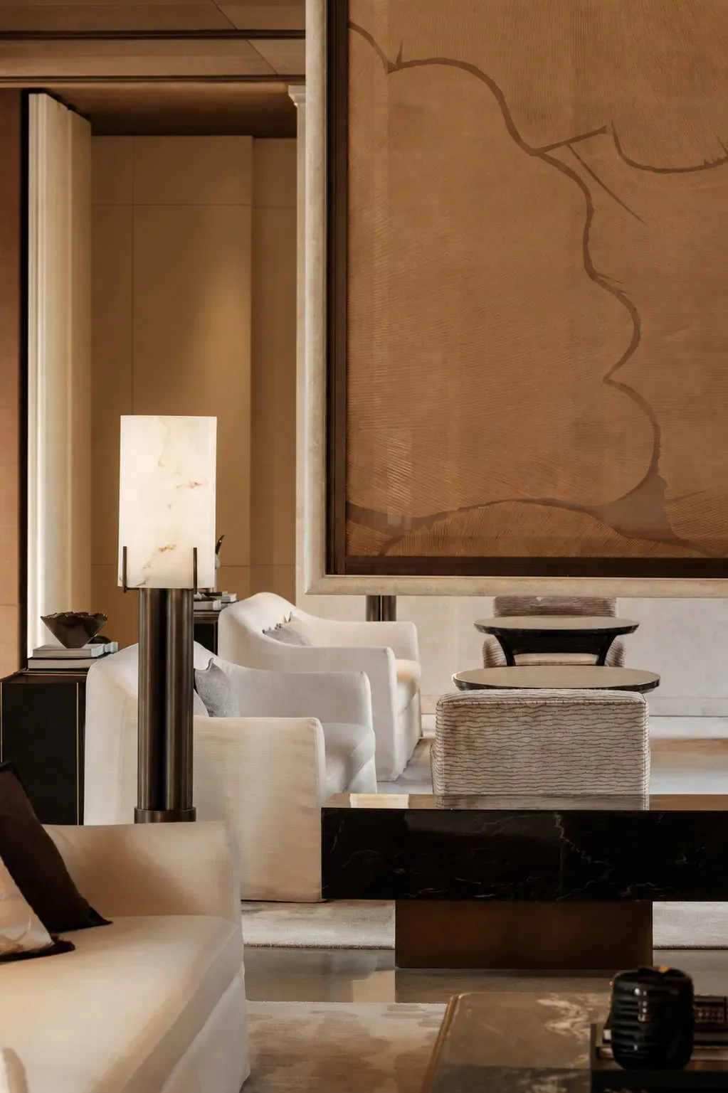 A well-lit living room with a couch, chair, and dining table, featuring a brown wall hanging and a warm atmosphere