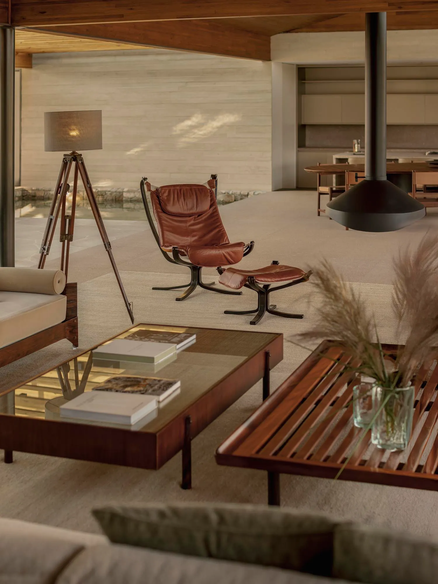 Cozy modern living space with a couch, chair, dining table, books, and a fireplace, lit by natural light through windows