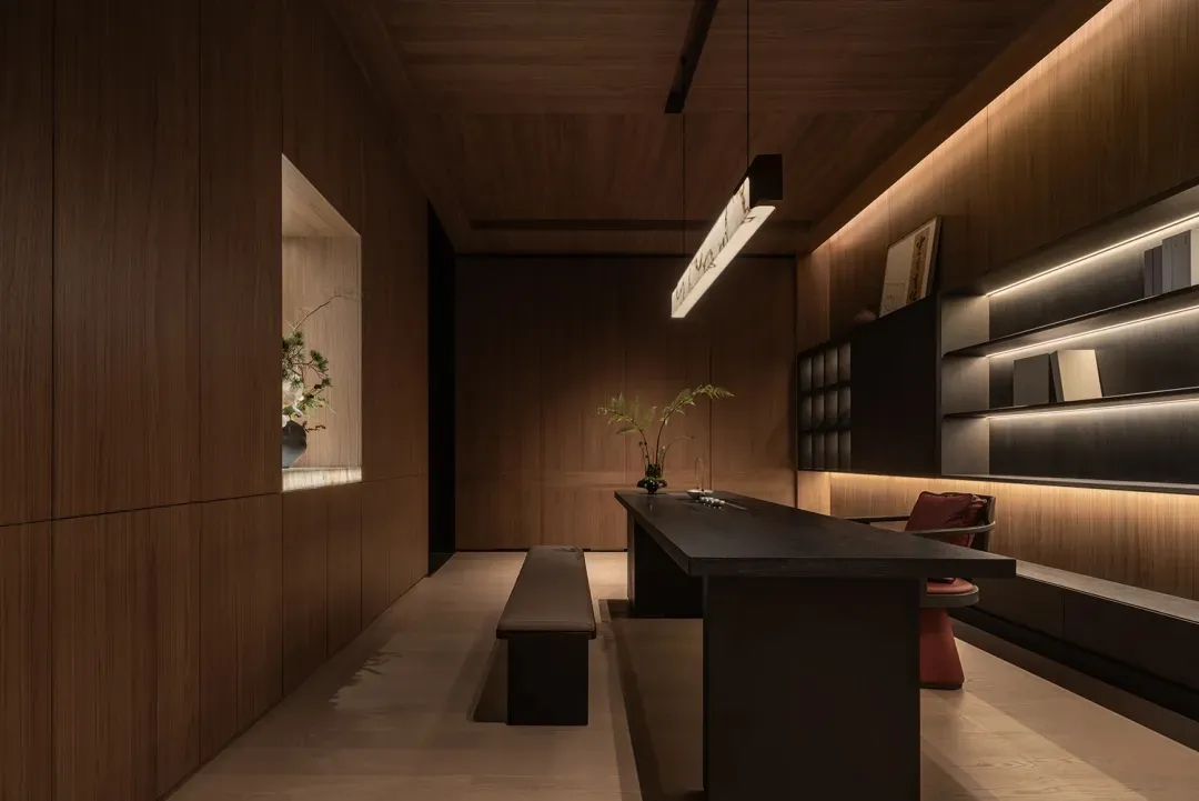 A modern kitchen and dining area with wooden floors and walls, featuring a dining table, chairs, and potted plants, creating a warm and inviting atmosphere