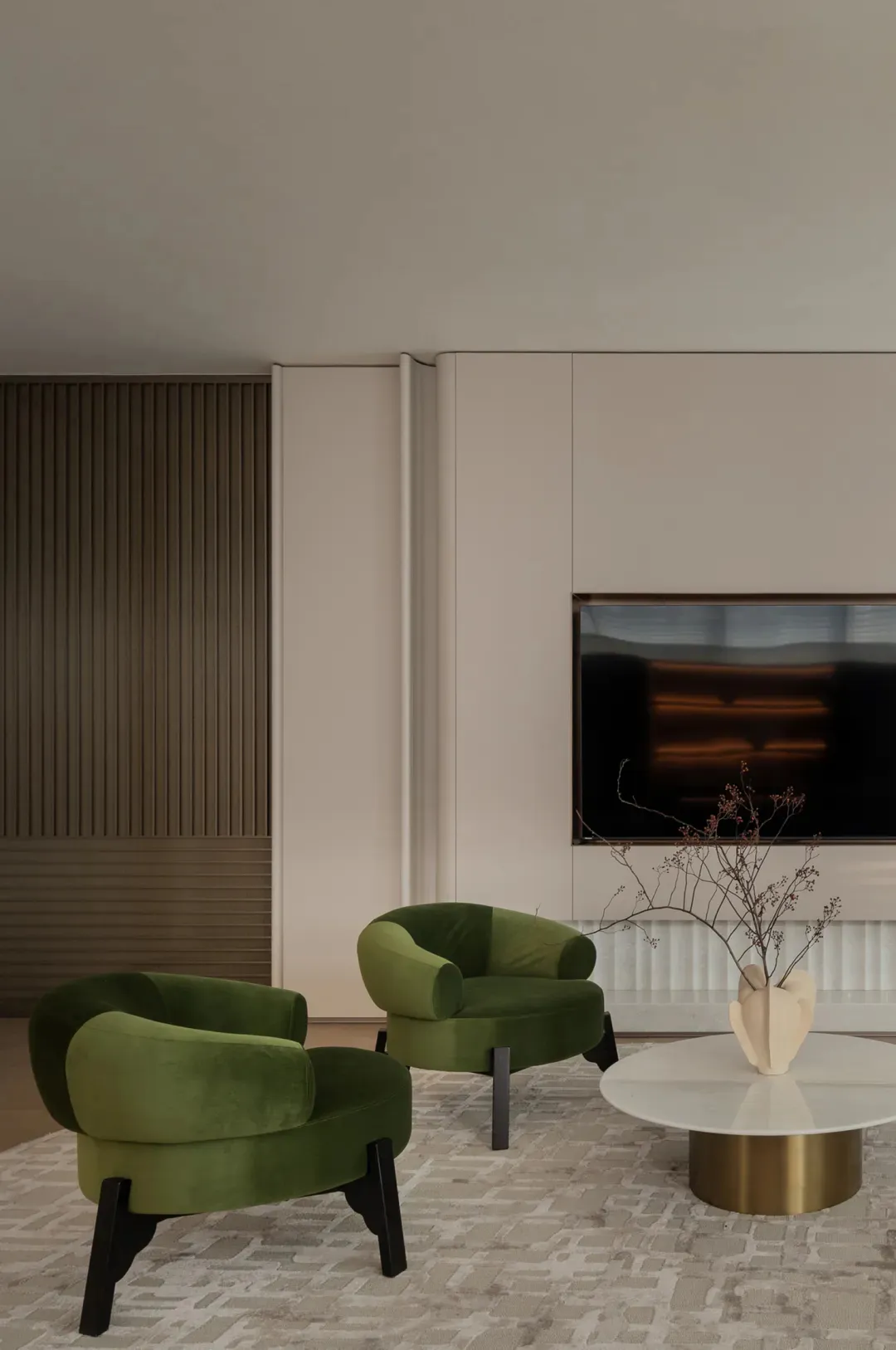 Comfortable living space with a flat screen TV, couch, and chair in a well-lit room with white walls and a modern design