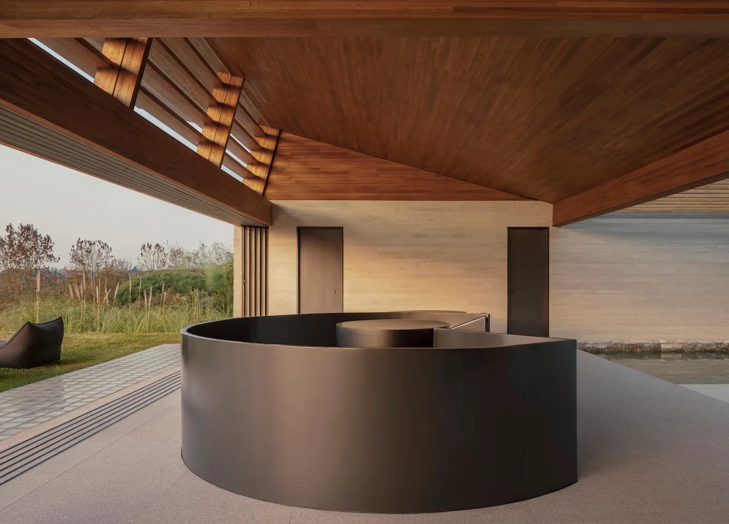 A modern living space with a large circular pool surrounded by a wooden deck and a wooden ceiling, creating a luxurious atmosphere