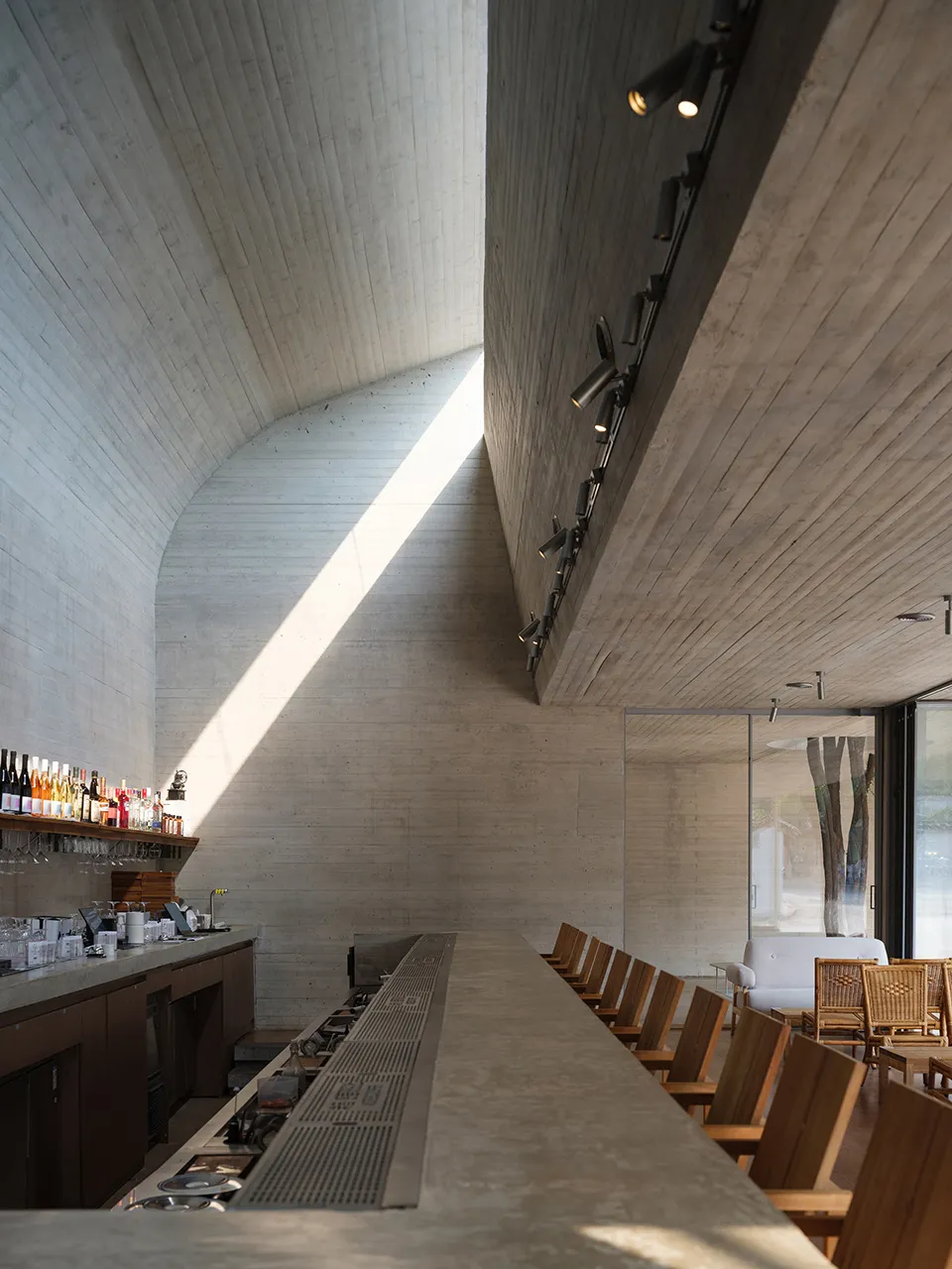 Modern bar with a marble counter, large glass window, and natural light, featuring several chairs and a contemporary design