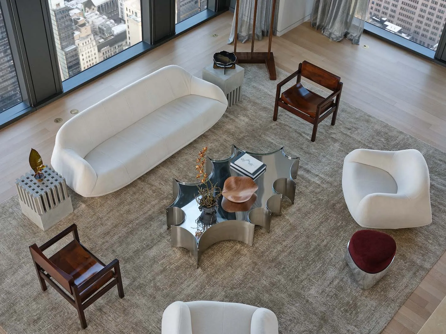 A modern living room with a white couch, a chair, and a coffee table, decorated with a rug and surrounded by various pieces of furniture and books, in a well-lit and inviting atmosphere