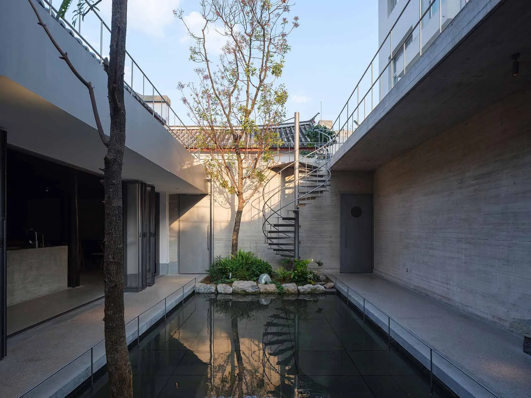A modern architectural scene featuring a large open space with a concrete staircase and a pond, surrounded by natural light and windows