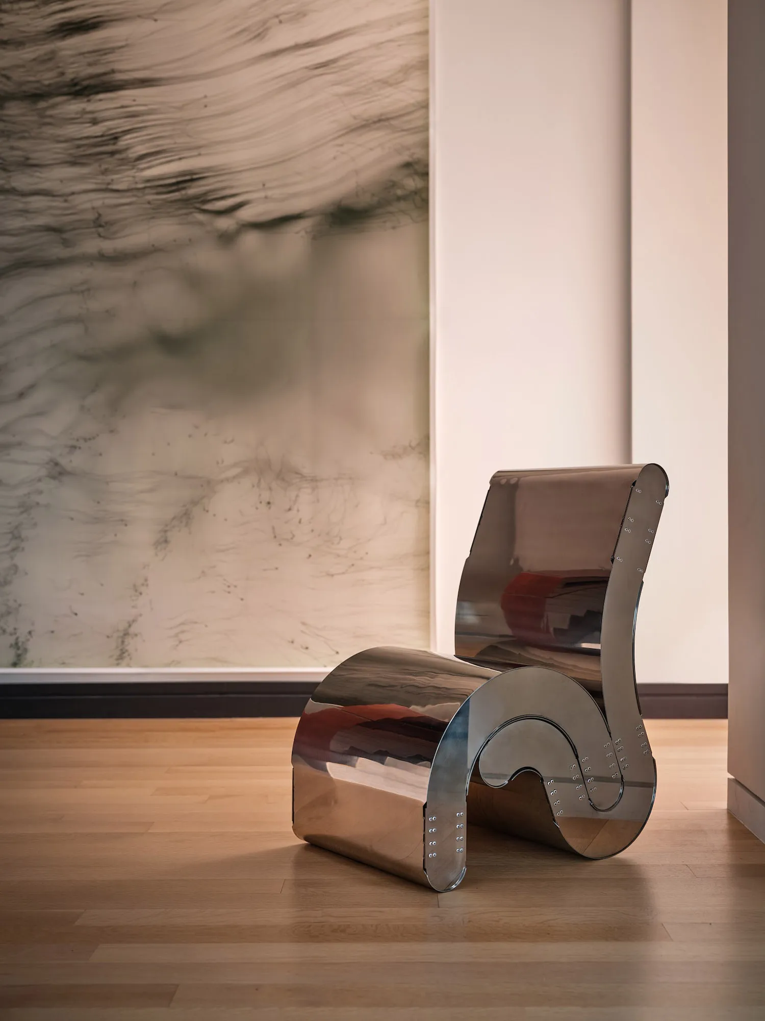 A modern room with a silver chair and a painting on the wall, featuring a clean and contemporary design