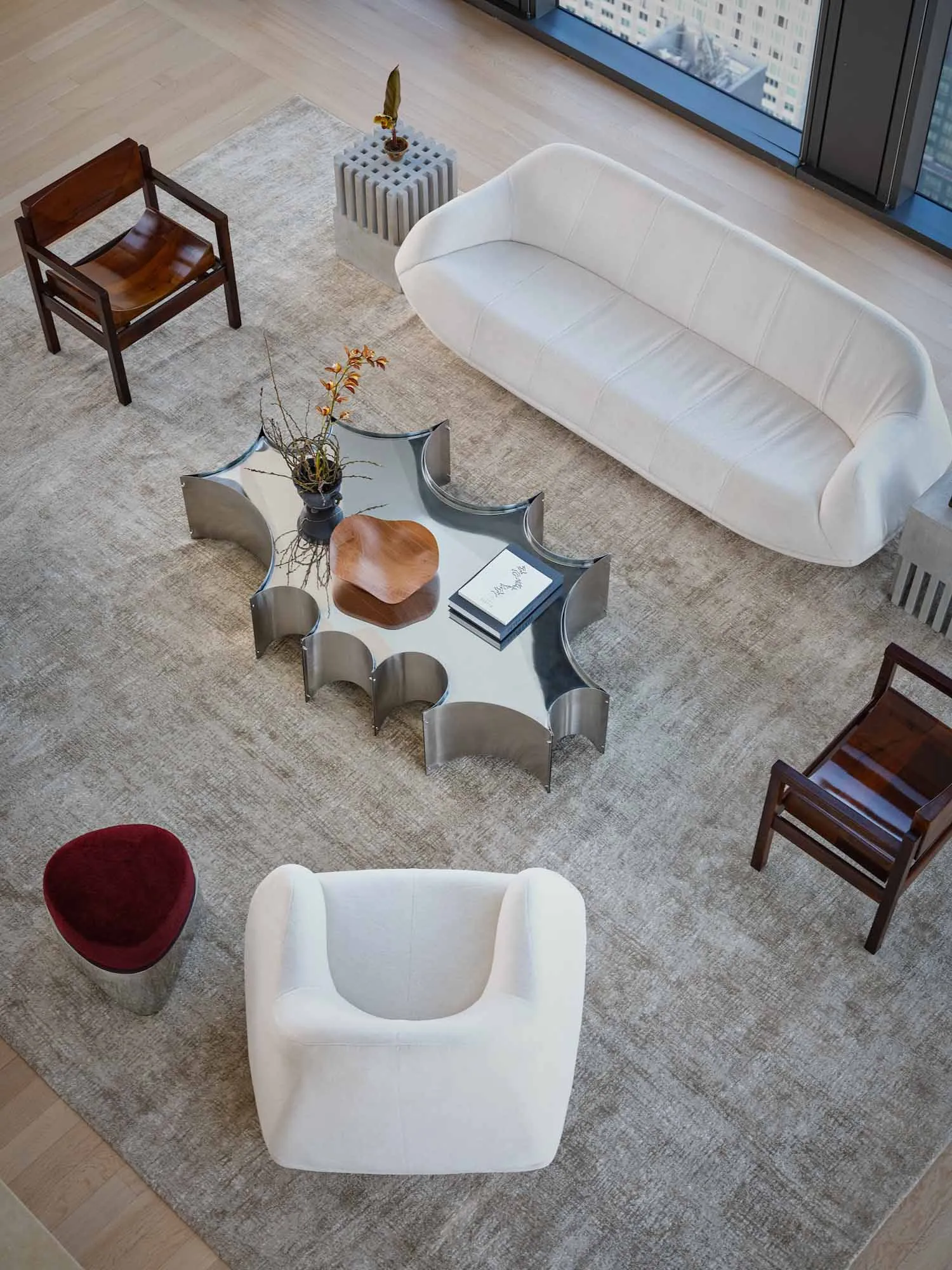 Cozy modern living space with a white couch, chair, and coffee table, surrounded by books and a rug, with natural light from a window