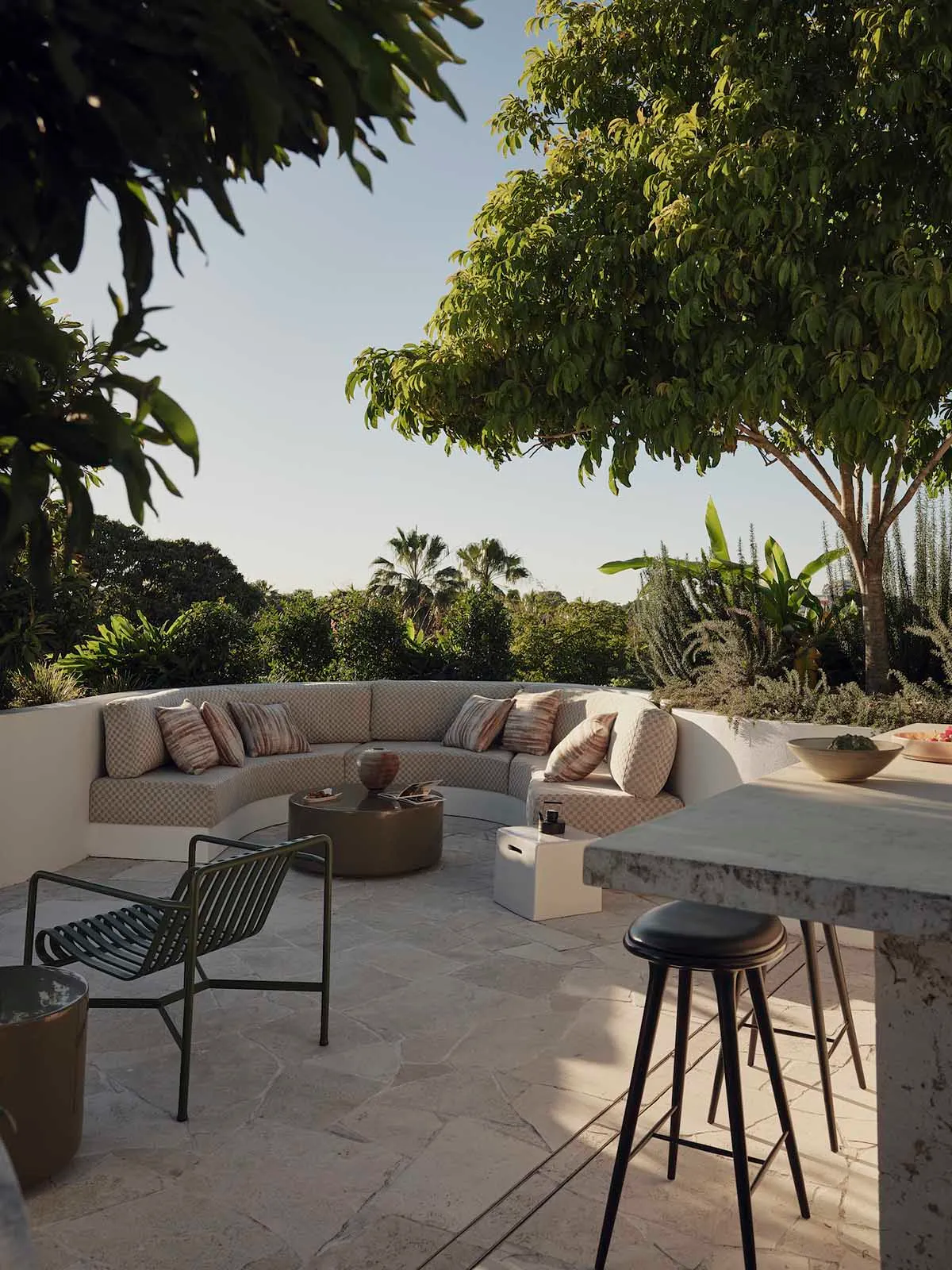 Brightly lit living room with a patio, white countertops, a dining table, and a couch, decorated with pillows and a vase