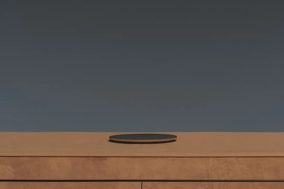 A room with a wooden table and a circular object on top, set against a grayish-brown background