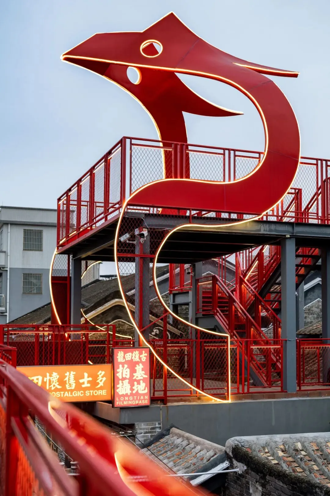 A modern staircase with a red railing and sculpture, set against a red and white background, with natural light and a mix of modern and traditional elements