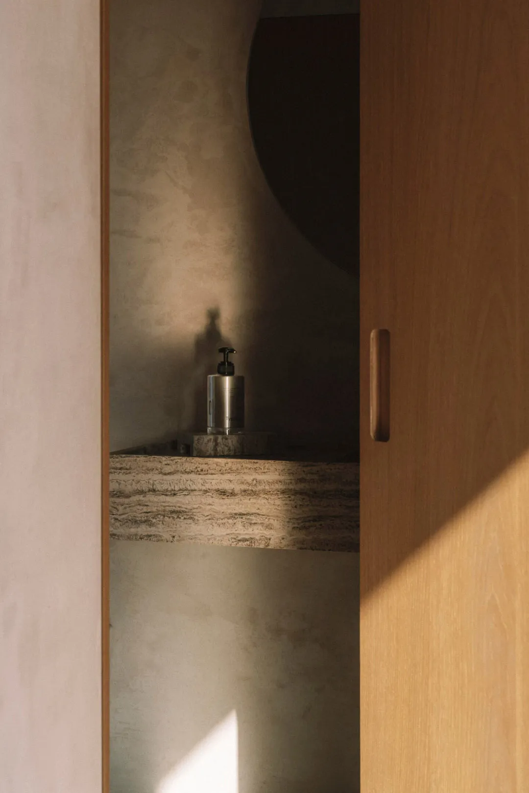 Bathroom with a sink and a bottle on the counter, surrounded by wooden surfaces and dim lighting