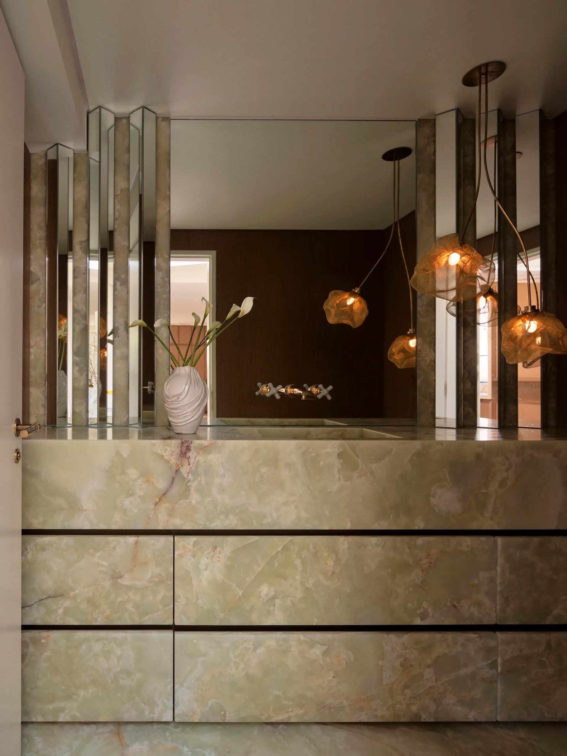 Modern bathroom with a marble countertop, a mirror, and a sink, surrounded by a clean and minimalist design, with natural light from a window