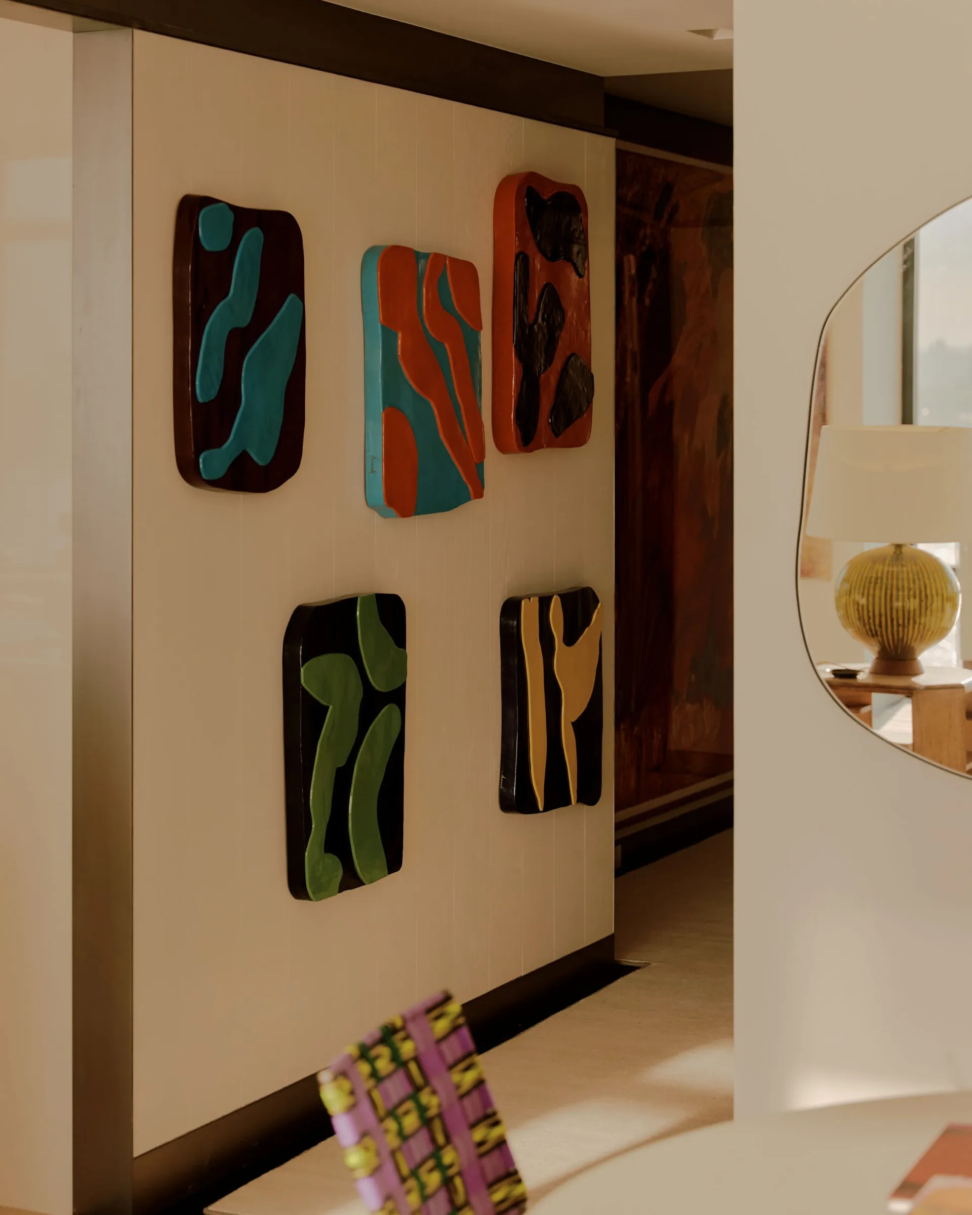 A modern room with a white wall and a mirror, featuring a collection of artworks and a clean minimalist design