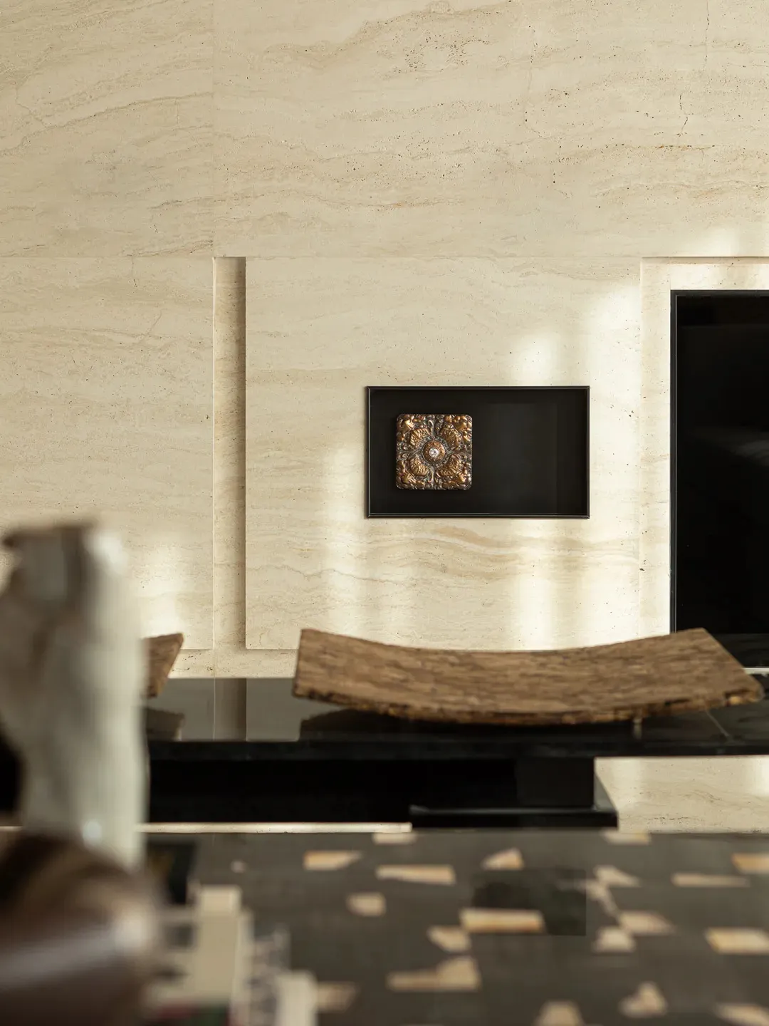 A classic modern dining room with a white marble wall, a wooden table, and a vase, set against a black frame, creating a sophisticated atmosphere