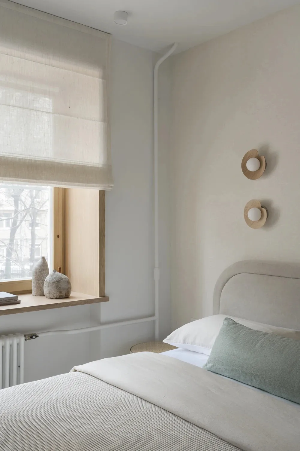 A well-lit bedroom with a bed, window, and lamp, featuring a cozy atmosphere and natural light