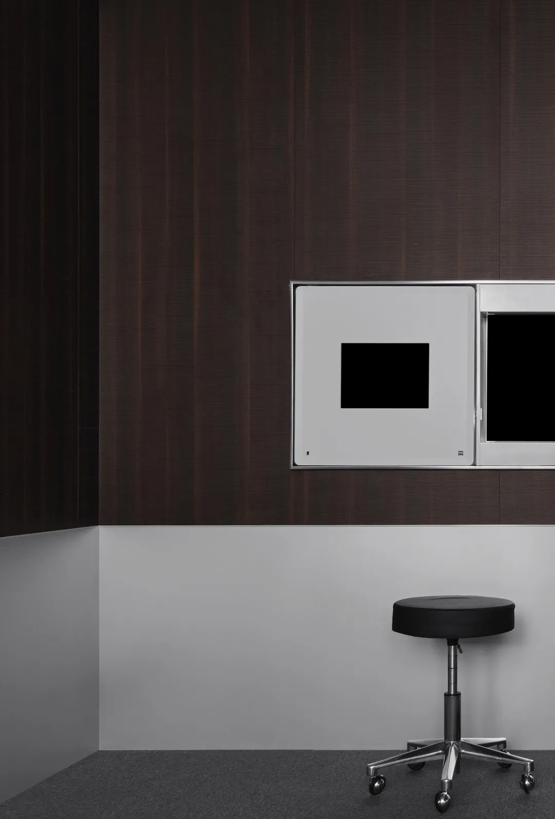 A modern living space with a wooden wall, a black table, and two square mirrors mounted on the wall, reflecting the room's interior in a dimly lit atmosphere