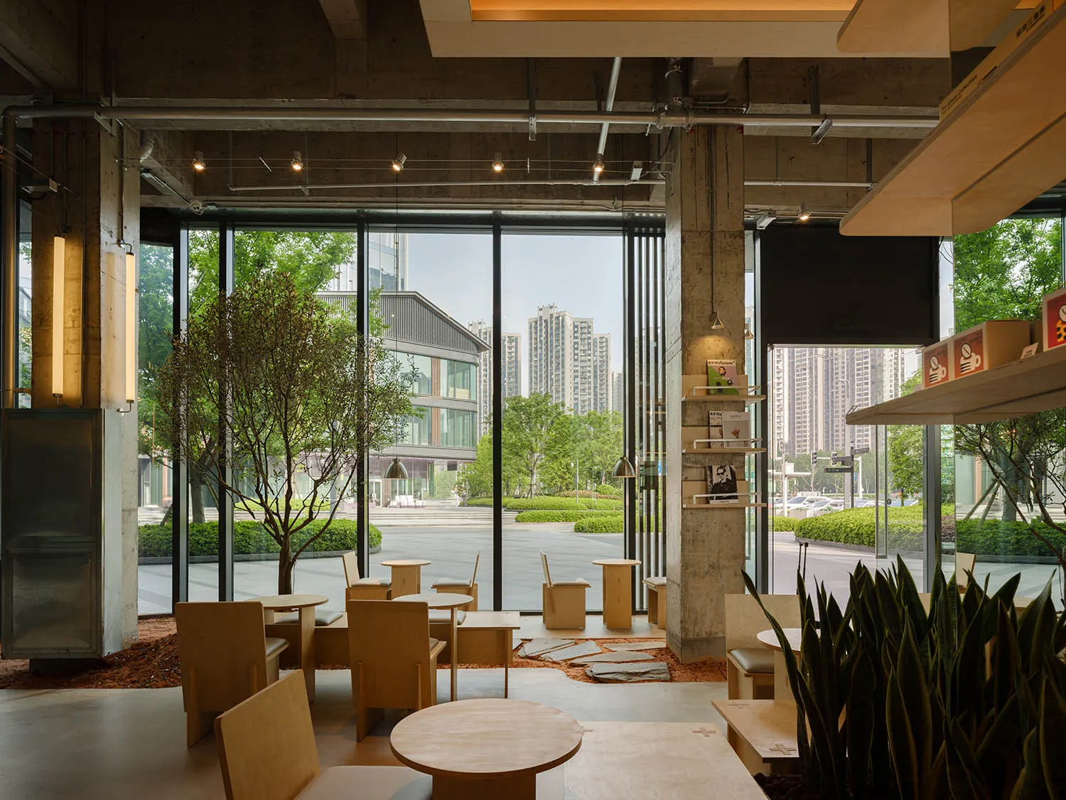 Modern restaurant with a large window, wood and concrete elements, and various pieces of furniture arranged to create a welcoming atmosphere