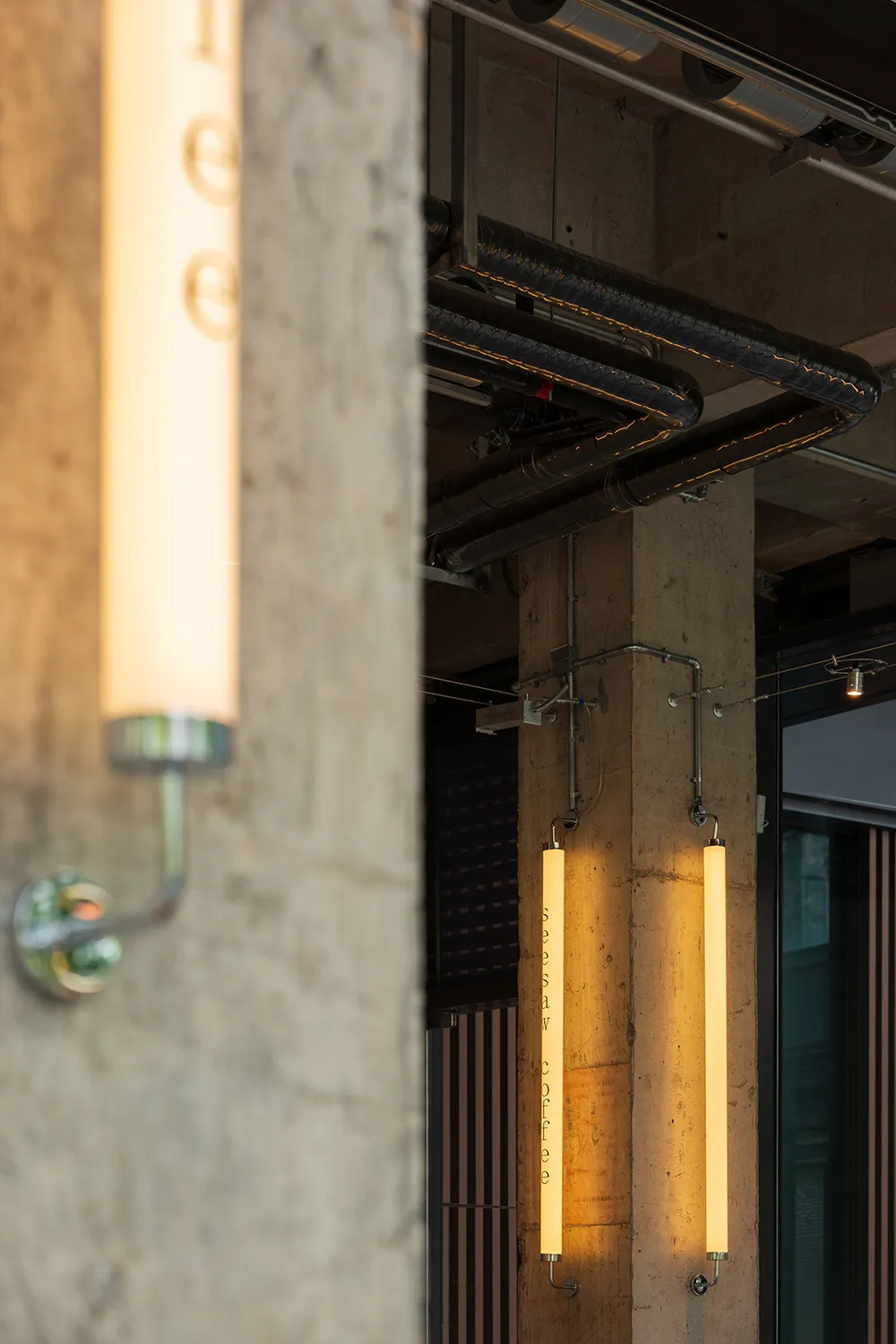 Dimly lit industrial space with a concrete floor and a pipe running along a concrete wall