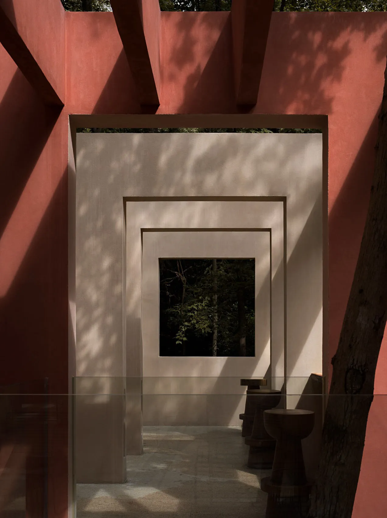 Dimly lit bathroom with two toilets, a red wall, and concrete walls