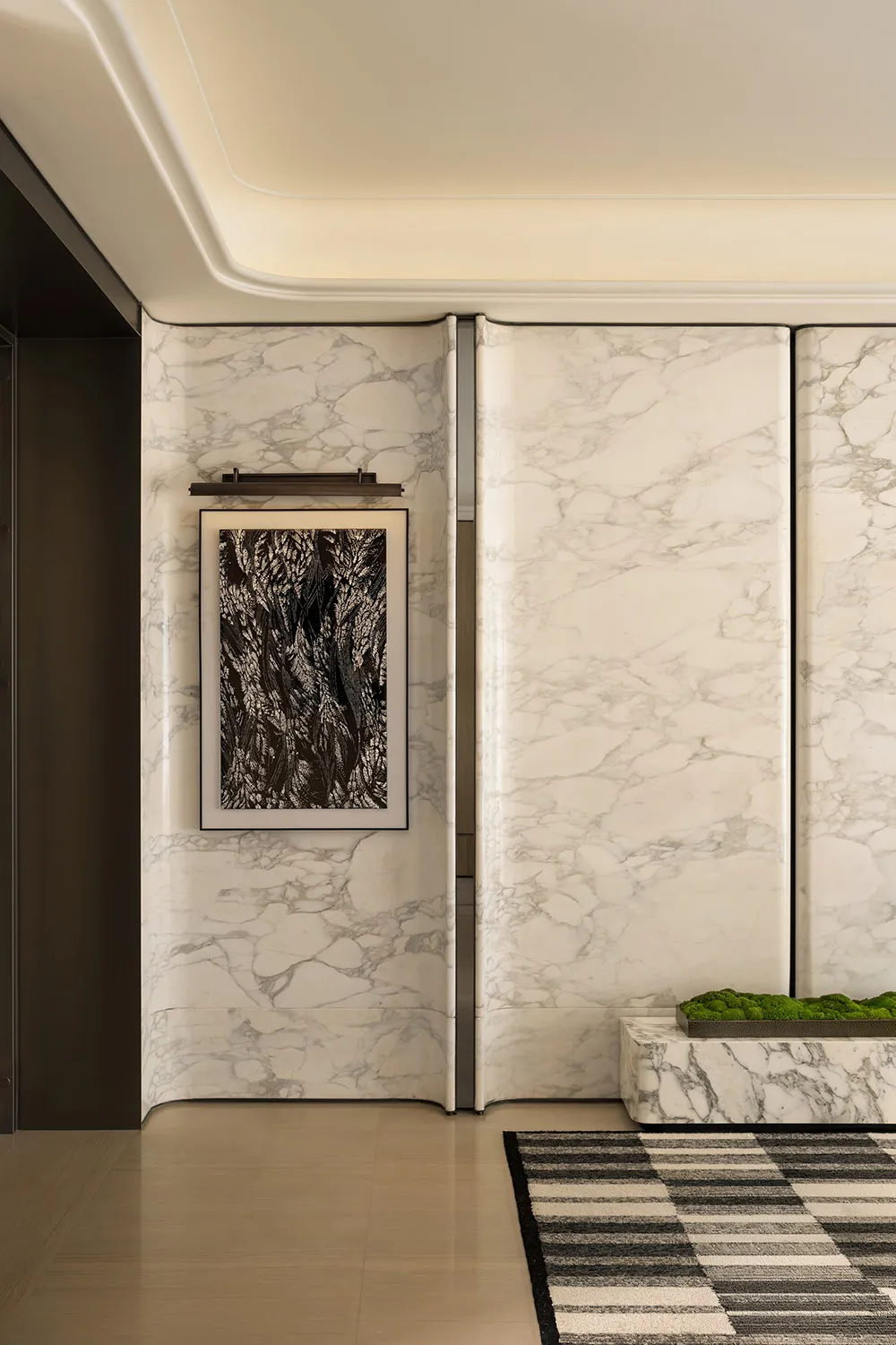 Bathroom with a white marble wall, a door, and a toilet, set in a dimly lit space with an intimate atmosphere