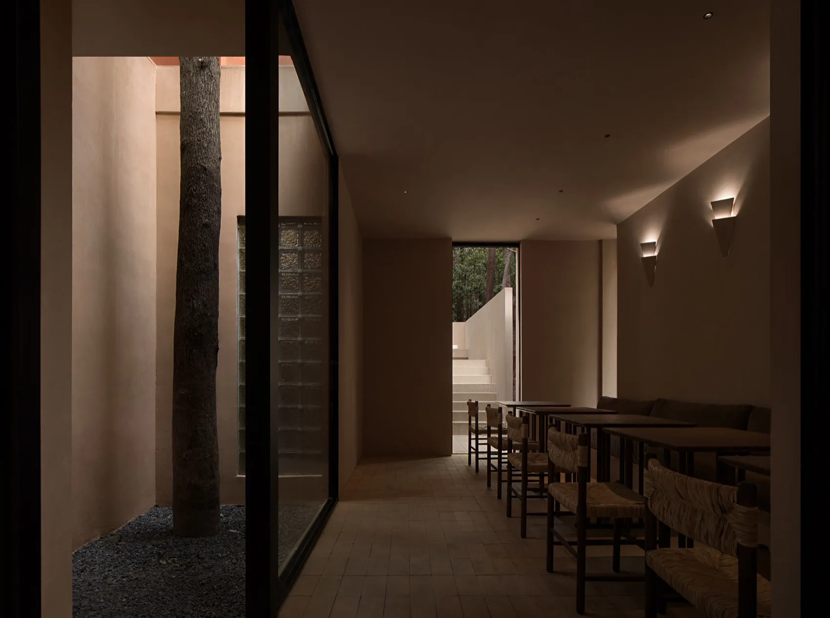 A well-lit restaurant with a modern design, featuring a dining area with tables and chairs, and a bar with a counter and stools