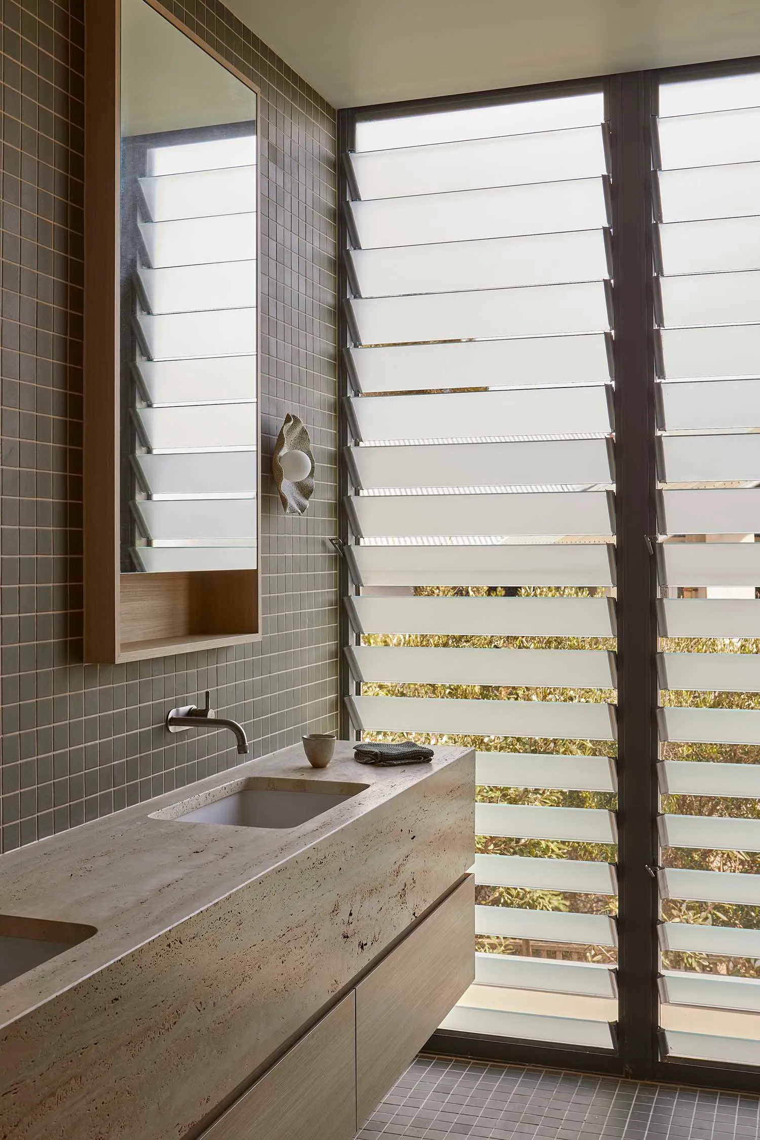 Bathroom with a tiled floor, wooden countertop, metal sink, and a window allowing natural light to enter