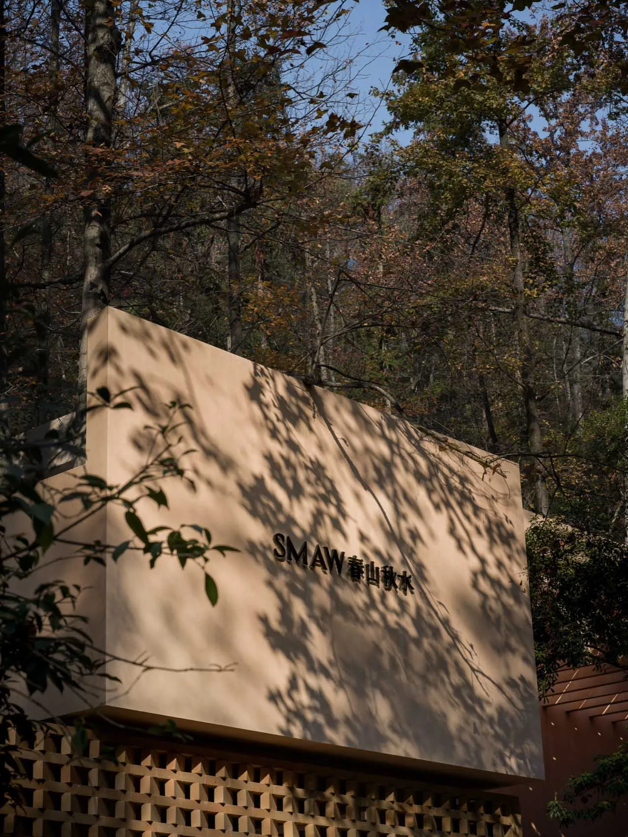 Photograph of a wooden cabin in a forest setting with tan-colored wood and natural light from the sun