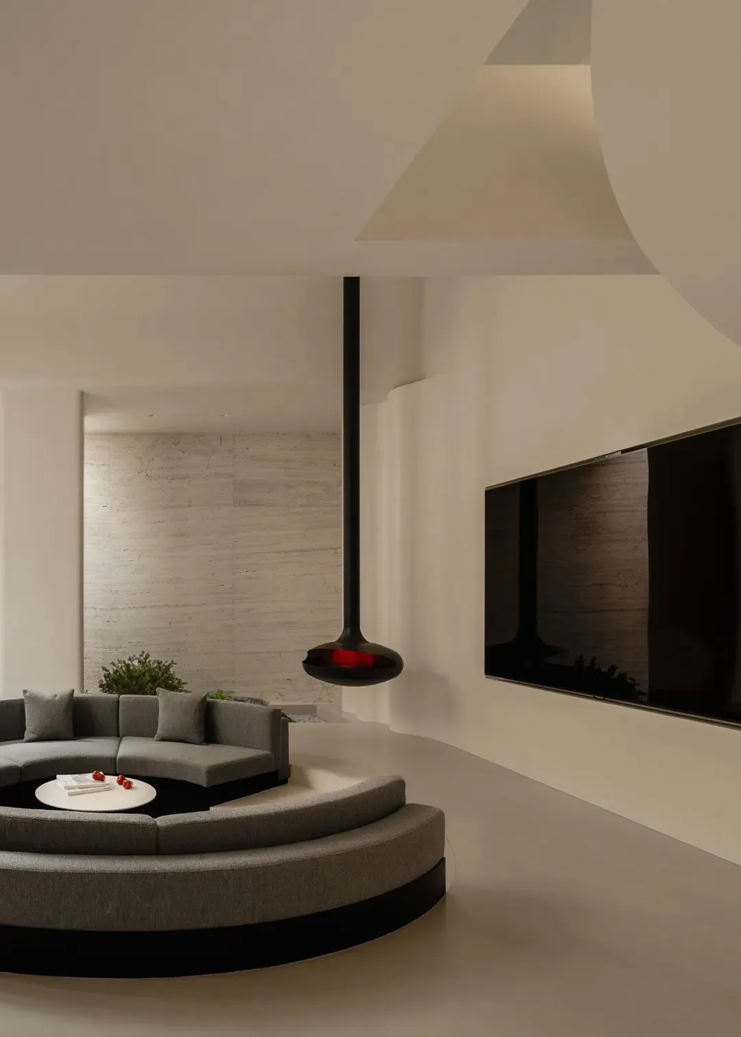 A well-lit living room with a modern design, featuring a large couch, a chair, and a TV mounted on the wall, surrounded by marble and wood accents
