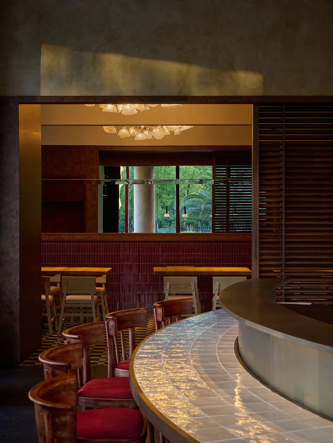 Cozy restaurant interior with a wooden counter, brown chairs, and a mix of natural and artificial lighting
