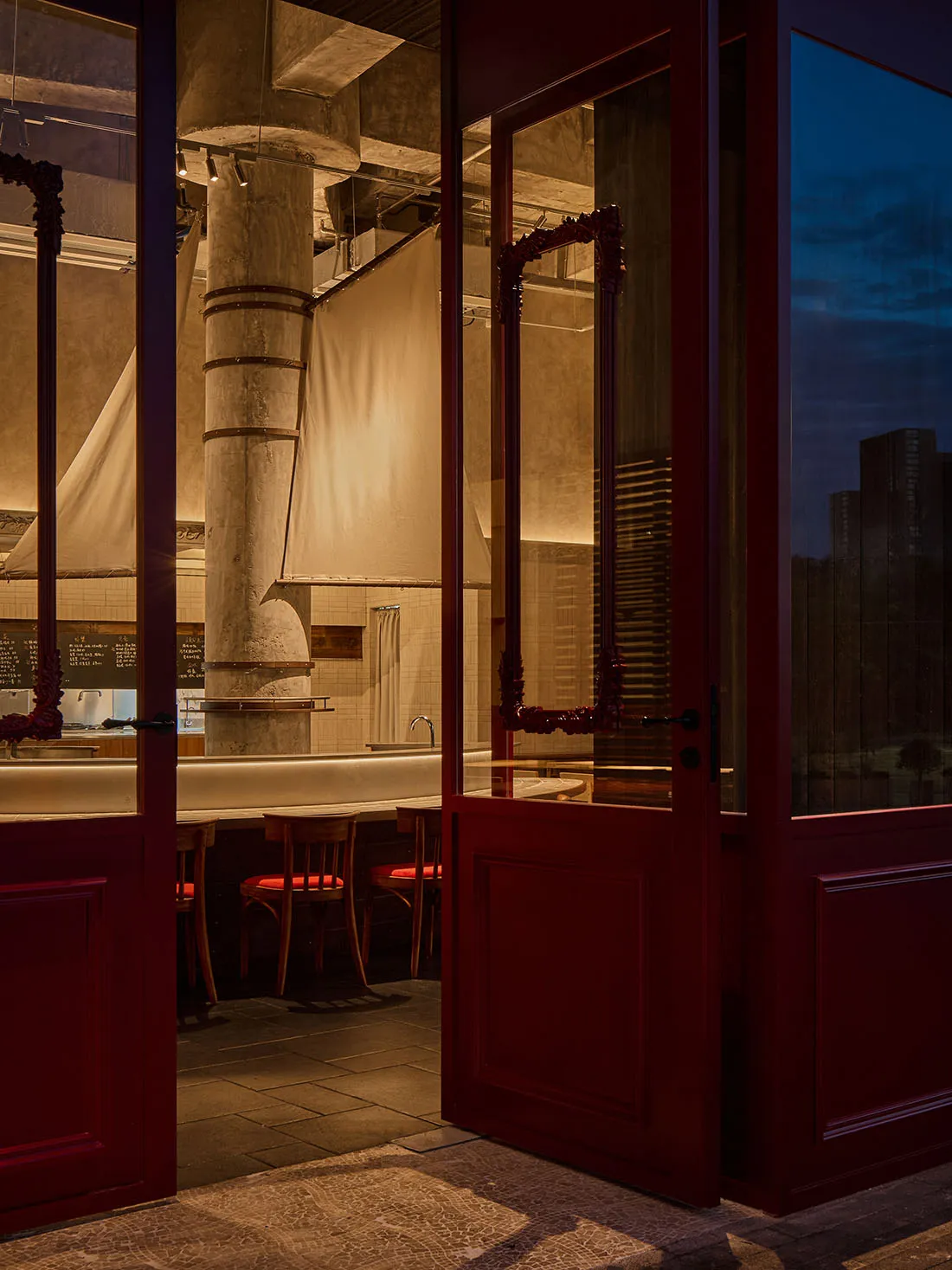 Cozy restaurant with a red door, white counter, and dim lighting, featuring a dining area with a table and chairs