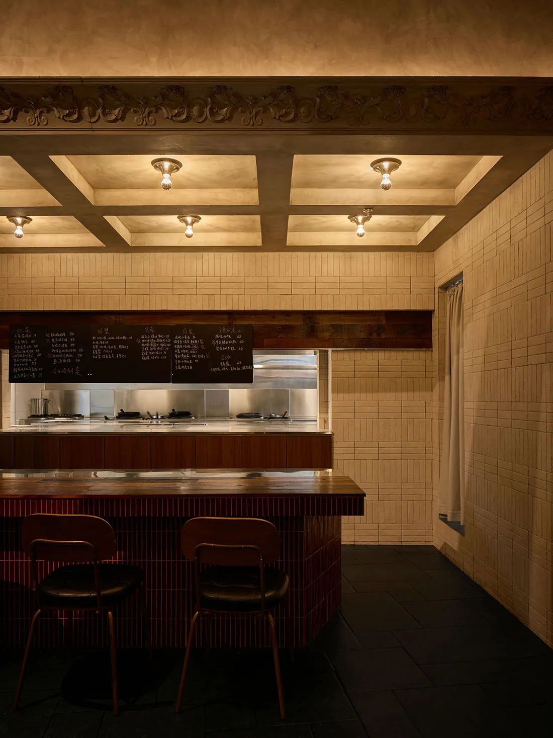 A warm and inviting restaurant interior with a wooden counter, brick elements, and soft lighting