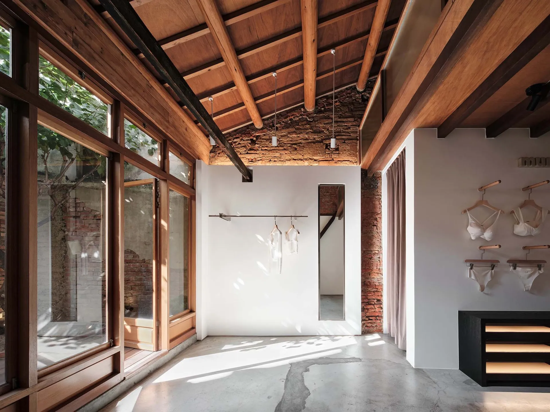 Brightly lit room with high ceiling, wood, and brick elements, natural light, and decorative accents