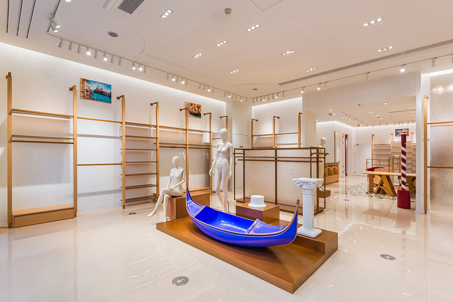 A modern store display featuring a blue boat-shaped object, a mannequin, and a vase, set in a retail space with a focus on creating an attractive shopping experience