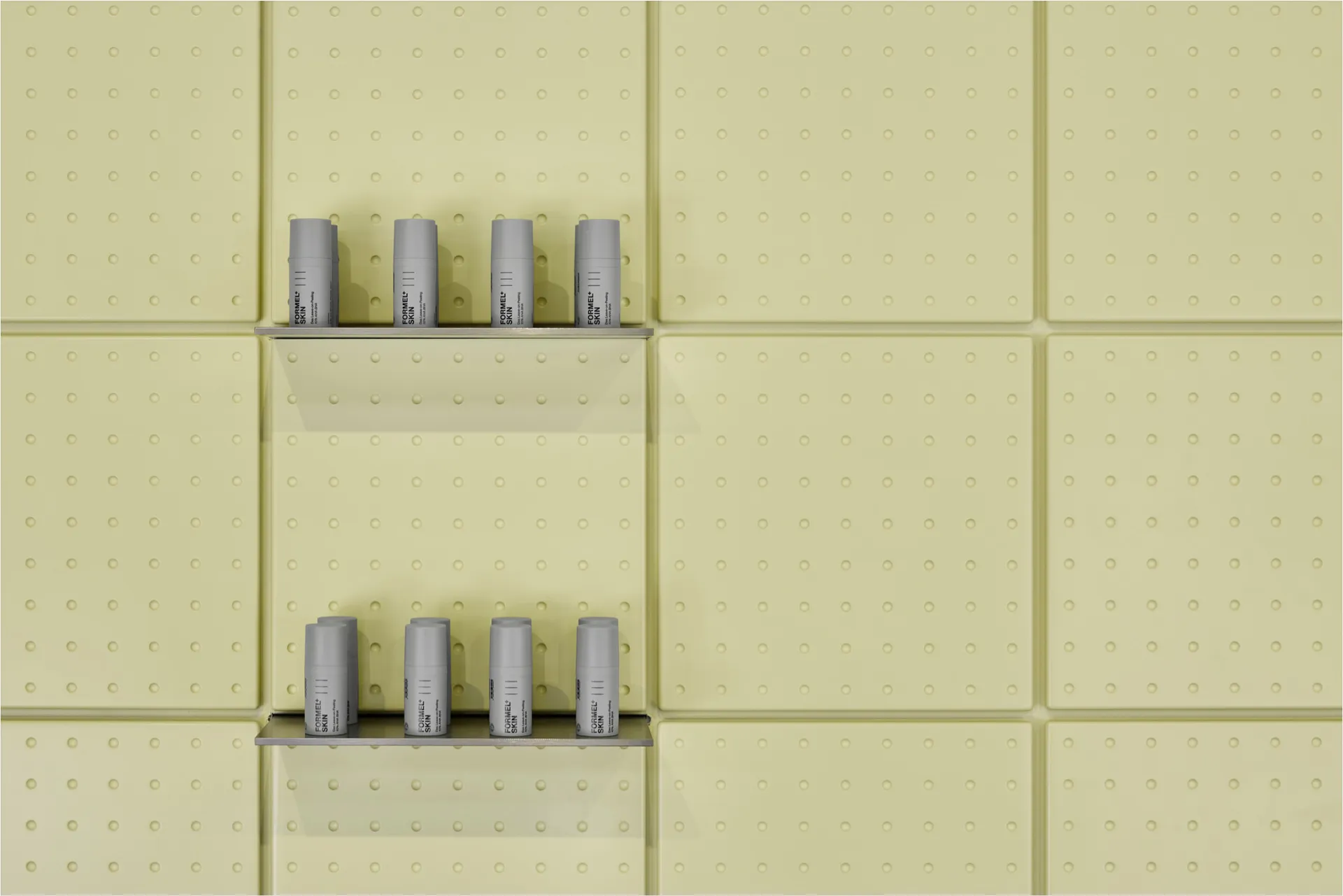 Four grey cosmetic bottles arranged on two floating metal shelves against a light pistachio green perforated wall panel system.