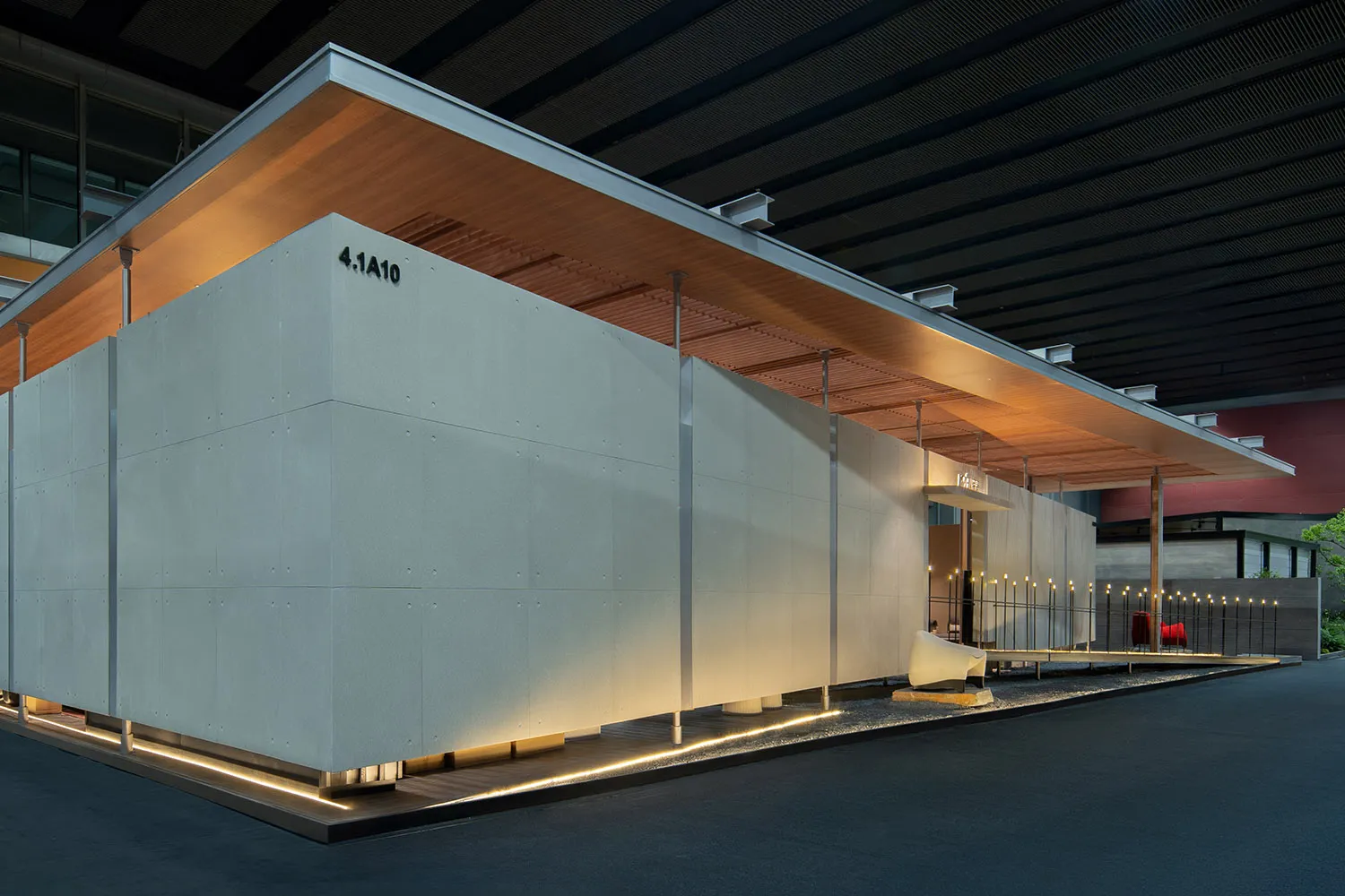 現代混凝土展館,採用大面積混凝土板、木質天花板懸挑,以及夜晚底部發光的線性LED燈。