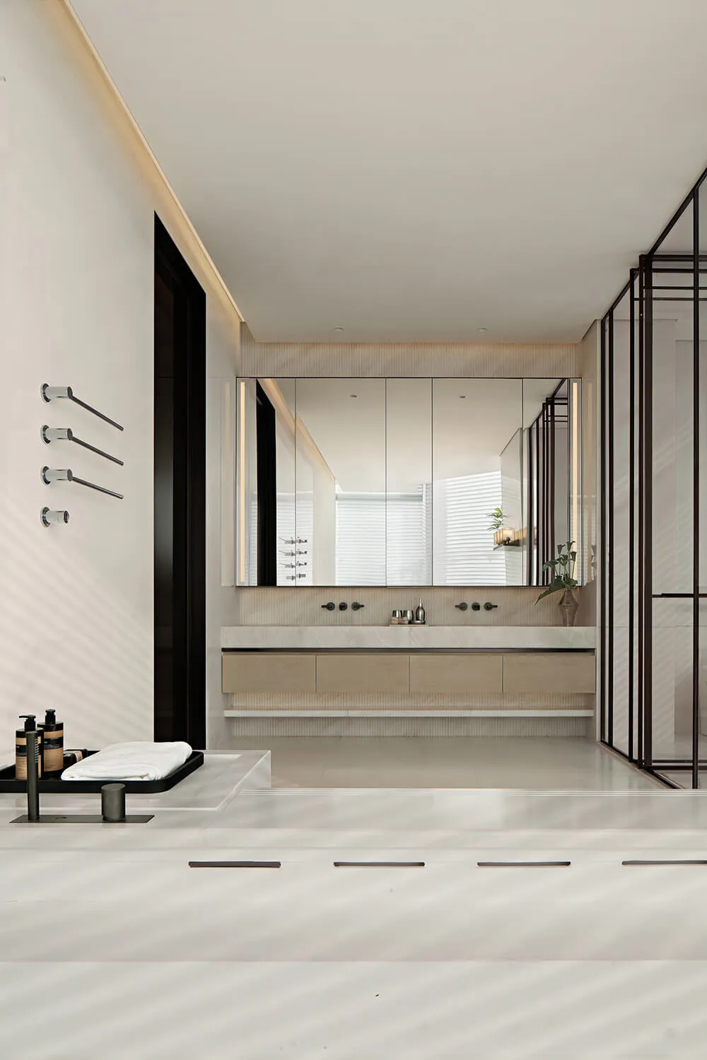 Modern minimalist bathroom with white marble surfaces, floating light-wood vanity, large backlit mirror, and black metal accents