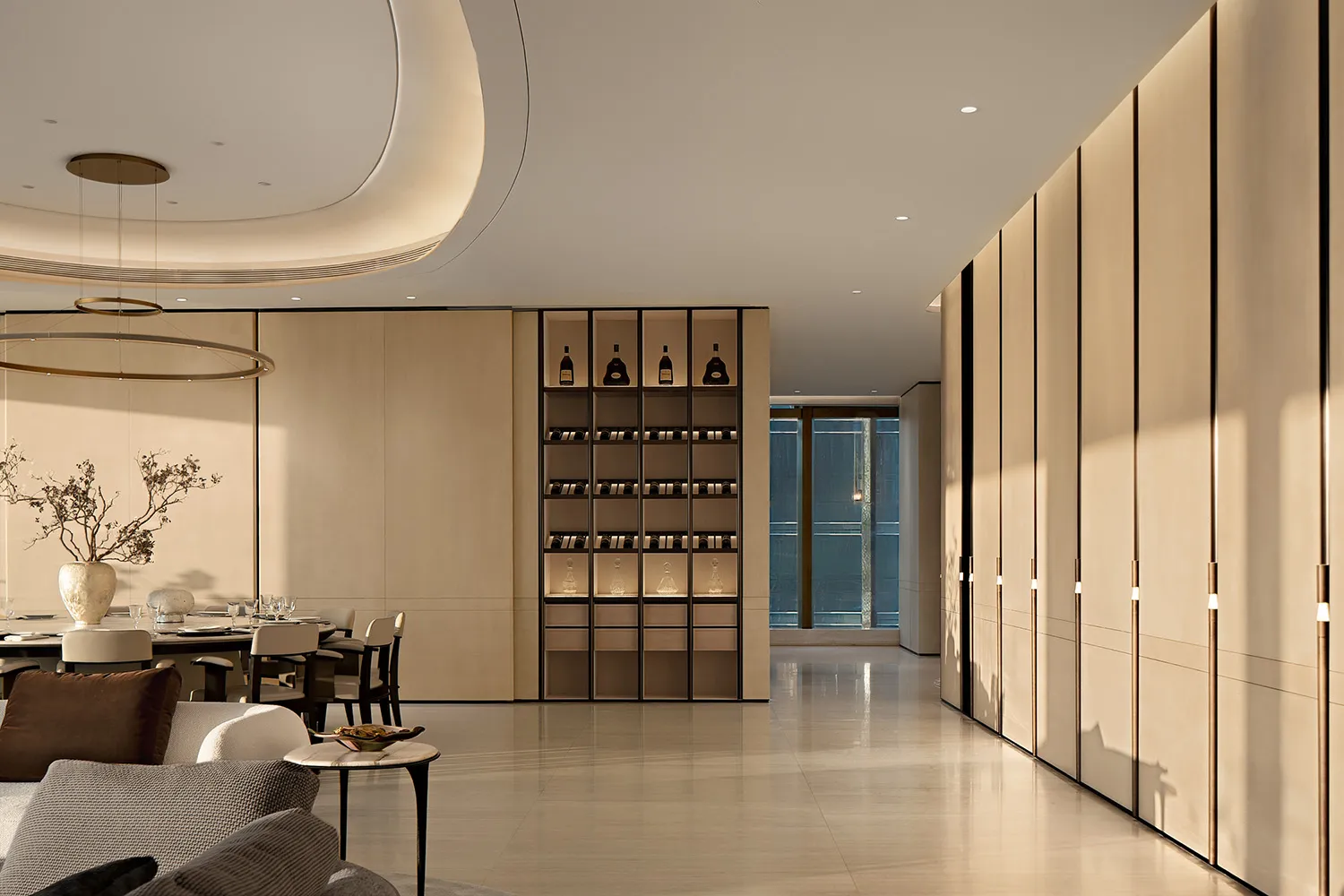 Modern luxury dining room with round chandelier, oak wine cabinet, and neutral-toned seating area