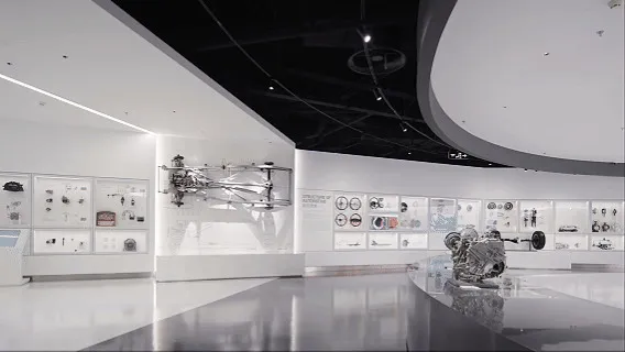 現代航空博物館展廳內部,懸掛飛機部件、牆面技術展示、拋光混凝土地板,以及戲劇性的弧形天花板。