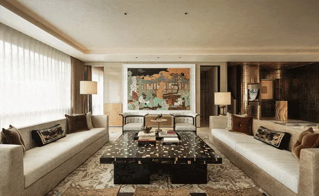 Elegant luxury living room with two beige sofas facing each other, a large black marble coffee table with gold inlay, and a colorful traditional Chinese landscape painting on the back wall.