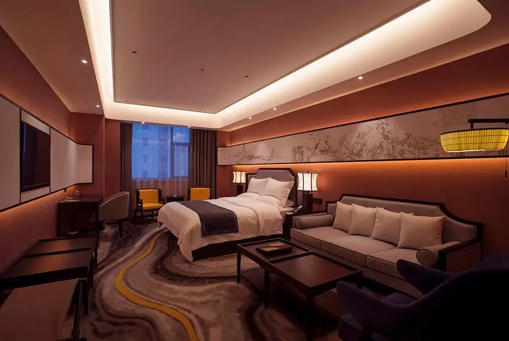 Modern luxury hotel bedroom featuring a large Chinese ink landscape painting, marble-patterned area rug, walnut furniture, and warm ambient lighting.