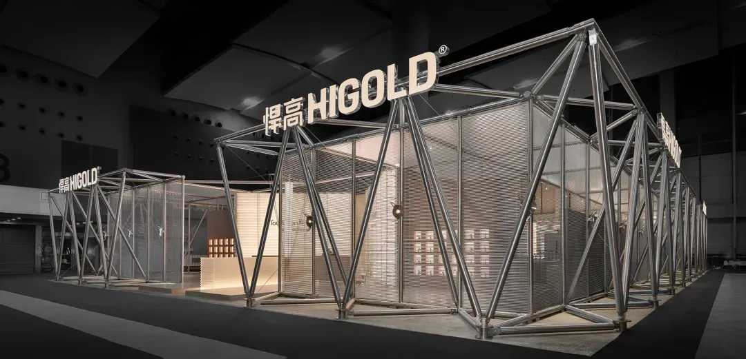 Large-scale geometric exhibition booth constructed from polished stainless steel frames and mesh panels, featuring the Higold brand name in illuminated signage, displayed in a modern exhibition hall.