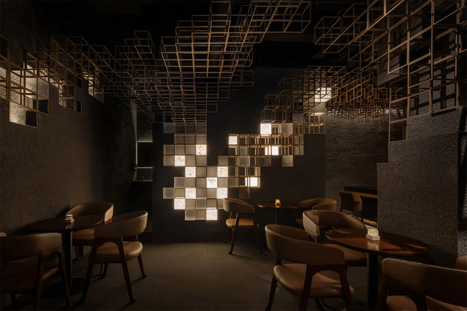 Modern restaurant interior featuring a large geometric light installation made of illuminated cubes, dark textured plaster walls, and warm brown leather dining chairs arranged around round wooden tables.