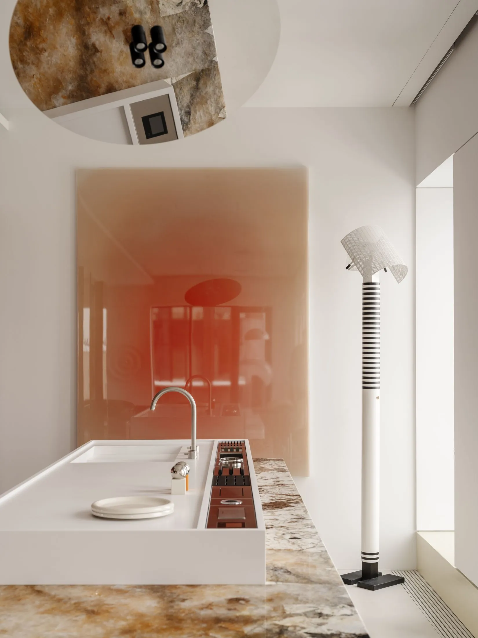 Modern minimalist kitchen with white island, chrome faucet, onyx countertop and backsplash, and a tall striped floor lamp.
