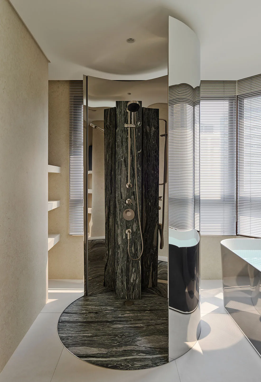 Modern luxury bathroom with a curved dark green marble shower room and freestanding white bathtub next to a large window with blinds.