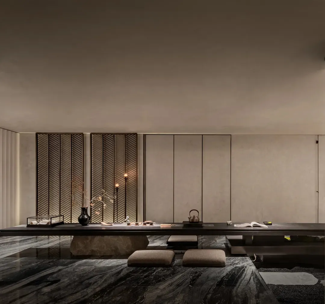 Modern Japanese-style tea room featuring polished dark marble floor, low wooden tea table, floor cushions, decorative lattice screen, and soft ambient lighting.